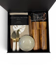 Housewarming kitchen gift box featuring two wood salt and pepper grinders, handcrafted ceramic dish, marble-handled cheese knives, solid cheese board, hand screen-printed linen tea towel and Tluxau chocolate